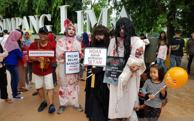 Masyarakat berfoto dengan anggota Kelompok Milenial Antihoaks yang melakukan kampanye melawan berita bohong dengan mengenakan kostum hantu. (Antara)