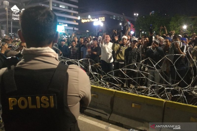 Seorang petugas kepolisian berusaha menenangkan massa aksi yang berupaya merusak pagar kawat berduri di depan Gedung Bawaslu, Jakarta, pada Selasa (21/9/2019). (ANTARA/Gilang Galiartha)	