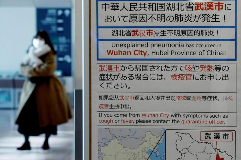 Seorang wanita menggunakan masker saat melewati papan pengumumam karantina mengenai kejadian luar biasa virus corona di Wuhan, China di terminal kedatangan bandara Haneda, di Tokyo, Jepang, Senin (20/1/2020). (katadata)