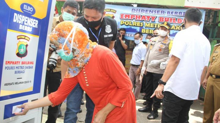 Seorang ibu mengambil beras bantuan dari program Dispenser Beras Polres Metro Jakarta Barat di Jakarta, Selasa, 12 Mei 2020. ANTARA News/HO-Polres Metro Jakarta Barat
