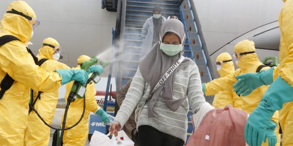 Petugas menyemprotkan disinfektan ke WNI yang baru datang dari Wuhan beberapa waktu lalu (Business Insider)