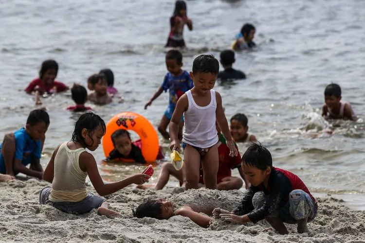 Anak-anak tengah menikmati bermain di pantai Ancol saat libur lebaran 2021 (Kompas)