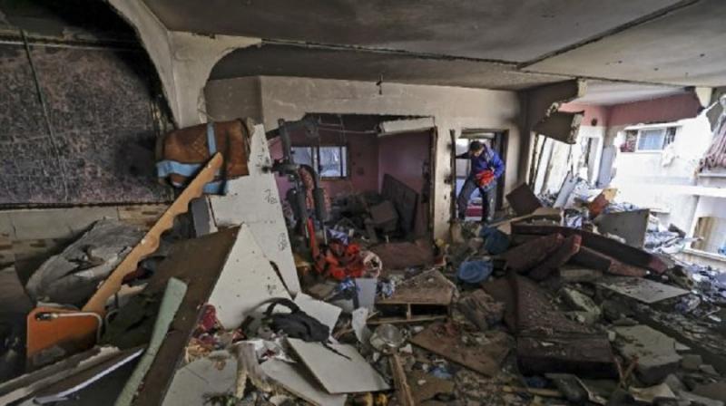 Seorang lelaki berjalan di dalam sebuah bangunan yang porak-poranda akibat dibom Israel pada Sabtu (15/5/2021). [AFP]