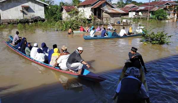 Sejumlah warga yang hendak menunaikan ibadah Shalat Idul Fitri 1440 Hijriah menggunakan perahu saat melintasi jalan yang terendam banjir di Teluk Barak, Putussibau, Kapuas Hulu, Rabu 5 Juni 2019. (Foto: Antara Foto)