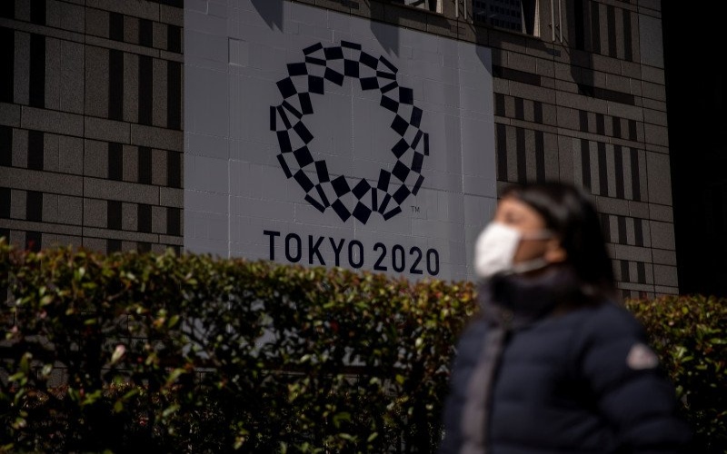 Seorang wanita menggunakan masker pelindung wajah, setelah mewabahnya virus korona, berjalan melewati spanduk menyambut Olimpiade Tokyo 2020 di depan gedung Pemerintah Kota Tokyo di Tokyo,Foto Antara