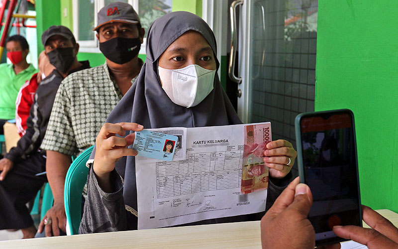 Warga antri menunggu giliran saat penyaluran bantuan sosial tunai (BST) dari Kementerian Sosial melalui PT Pos Indonesia di kawasan Kelurahan Kembangan, Meruya, Jakarta Barat, Minggu (25/07).  Robinsar Nainggolan 