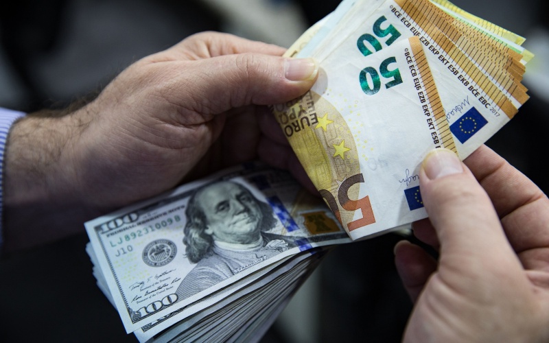 Seorang pria menghitung lembaran uang euro dan dolar AS. (Bloomberg)