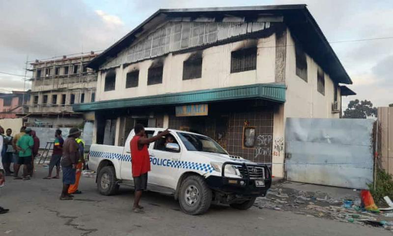 Mobil polisi terparkir di luar toko yang terbakar,  di mana tiga mayat ditemukan. (Foto: AFP)