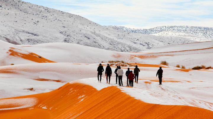  Wisatawan melihat salju yang menutupi sebagian Gurun Sahara di Kota Ain Sefra di Aljazair. Salju menutupi bukit pasir merah ini merupakan kejadian yang sudah ketiga kalinya dalam 37 tahun. Zineddine Hashas/Geoff Robinson