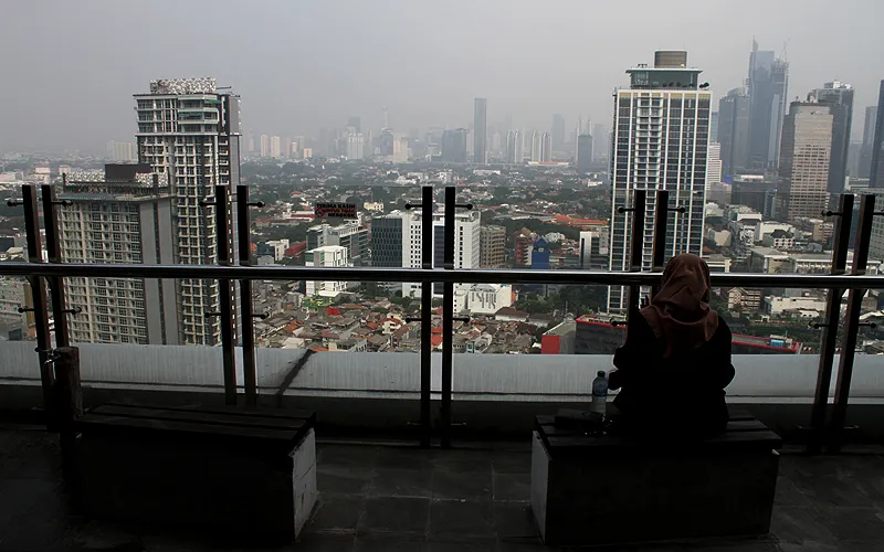 DKI Jakarta kembali menempati ranking pertama kualitas udara terburuk di dunia. Catatan IQ Air menunjukkan AQI US Jakarta berada di angka 196 yakni kategori kualitas udara tidak sehat. Warga berswafoto dengan latar belakang deretan gedung bertingkat tersamar kabut polusi udara di Perpustakaan Nasional, Medan Merdeka Selatan, Jakarta Pusat, Senin (20/6). Robinsar Nainggolan