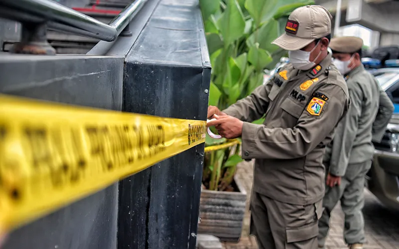 Petugas gabungan dari Satpol PP dan Kepolisian memasang garis batas penyegelan saat penutupan operasional Holywing Gold Kelapa Gading, Jakarta Utara, Selasa (28/6). Satpol PP DKI Jakarta menutup 12 cabang Holywings secara serentak pada hari ini, Penutupan tersebut itu dilakukan usai Gubernur DKI Jakarta Anies Baswedan mencabut izin usaha. Robinsar Nainggolan