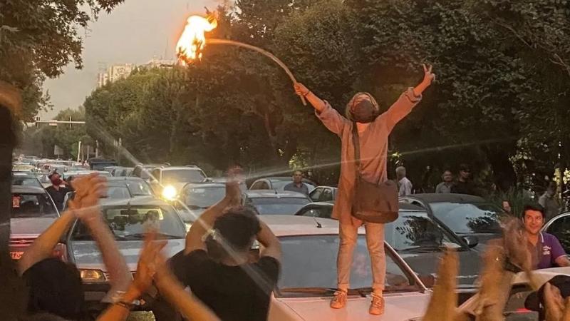 Seorang wanita membakar jilbabnya dalam aksi protes di Teheran, Iran (bbc.com)