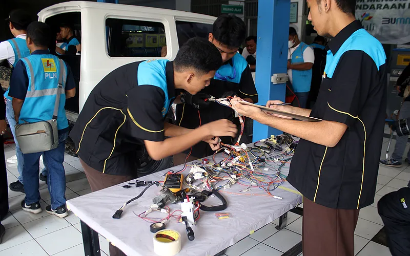 General Manager PLN Unit Induk Distribusi Jakarta Raya Lasiran (kanan) berbincang dengan Kepala Sekolah SMKN 26 Jakarta M. Bakri Akkas (ketiga kanan) dan Siswa SMKN 26 Jakarta saat kunjungan di Bengkel Otomotif SMK Negeri 26 Jakarta, Jakarta Timur, Rabu (13/9/2023). PLN Unit Induk Distribusi Jakarta Raya bekerjasama dengan Dinas Pendidikan Provinsi DKI Raya dan SMK 26 Jakarta menggelar program ELVIS (Electric Vehicle Conversion) atau konversi kendaraan berbahan bakar minyak menjadi kendaraan lis