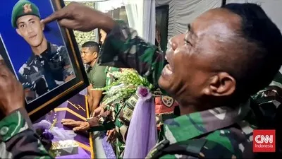 Serma Kristian Namo, ayah dari Prada Lucky Chepril Saputra Namo menangis dan sambil menunjuk foto anaknya saat jenazah tiba dirumah duka. CNN Indonesia/Elly