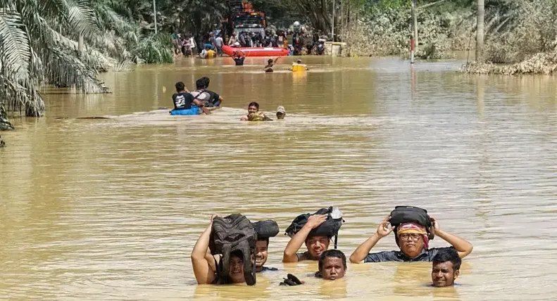 Ilustrasi: Warga mengarungi banjir setinggi leher orang dewasa di Kuala Simpang, Aceh Tamiang, Aceh, 30 November 2025. (BBC)