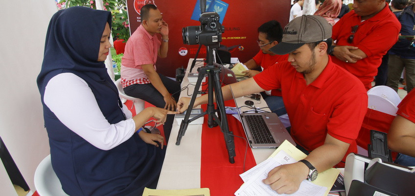 Petugas Imigrasi Kelas I Jakarta Pusat melayani warga dalam membuat paspor saat peluncuran mobil paspor keliling di Ancol, Jakarta, Minggu (29/10) (Foto: Antara)