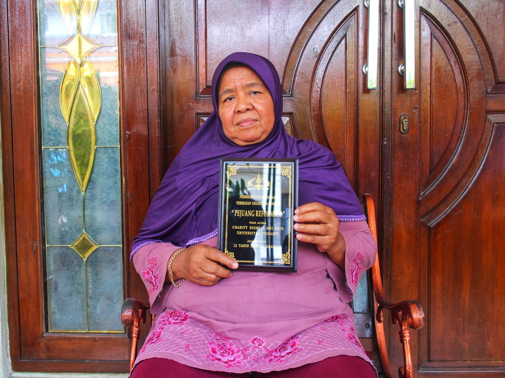Ibu Lasmiati memegang plakat  gelar Pejuang Reformasi untuk putranya Heri Hartanto (Foto: Januardi Husin)