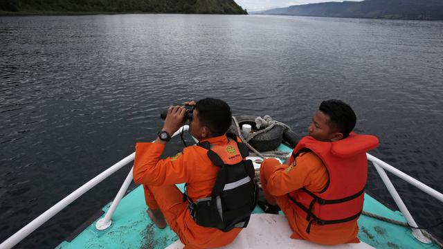 Tim SAR menggunakan teropong saat proses pencarian korban KM Sinar Bangun di Danau Toba, Sumatra Utara, Rabu (20/6). Sebelumnya, KM Sinar Bangun yang mengangkut 128 penumpang tenggelam di Danau Toba pada Senin (18/6) sore. Foto: AP/Binsar Bakkara